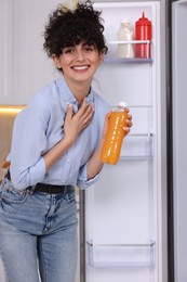 Photo of Smiling food blogger with bottle of juice in kitchen