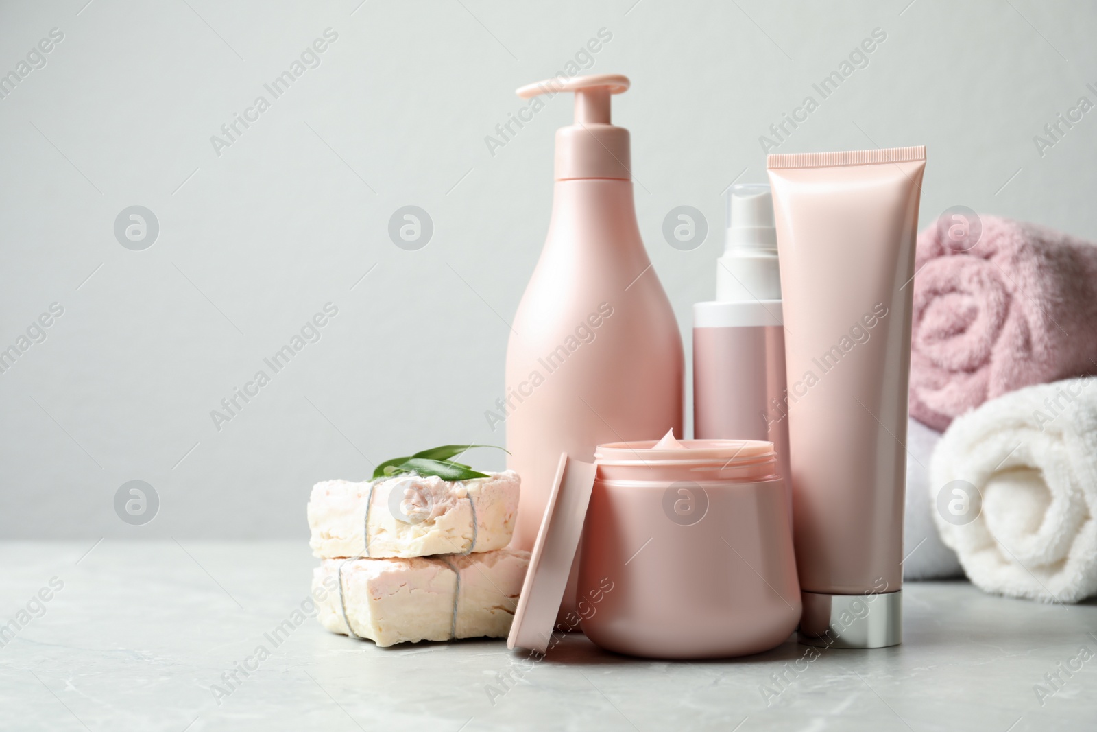 Photo of Set of hair care cosmetic products and soap bars on light grey marble table. Space for text