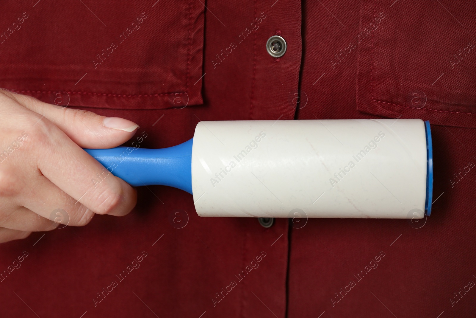 Photo of Woman cleaning red shirt with lint roller, closeup