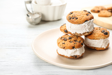 Photo of Sweet delicious ice cream cookie sandwiches on white wooden table. Space for text