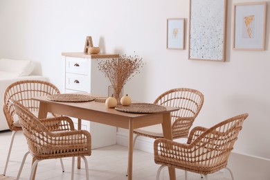 Photo of Dining room interior with wooden table and wicker chairs