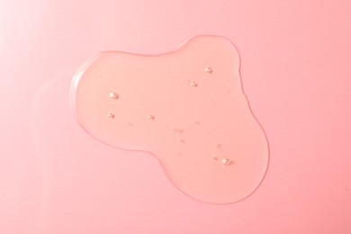 Drop of hydrophilic oil on pink background, top view
