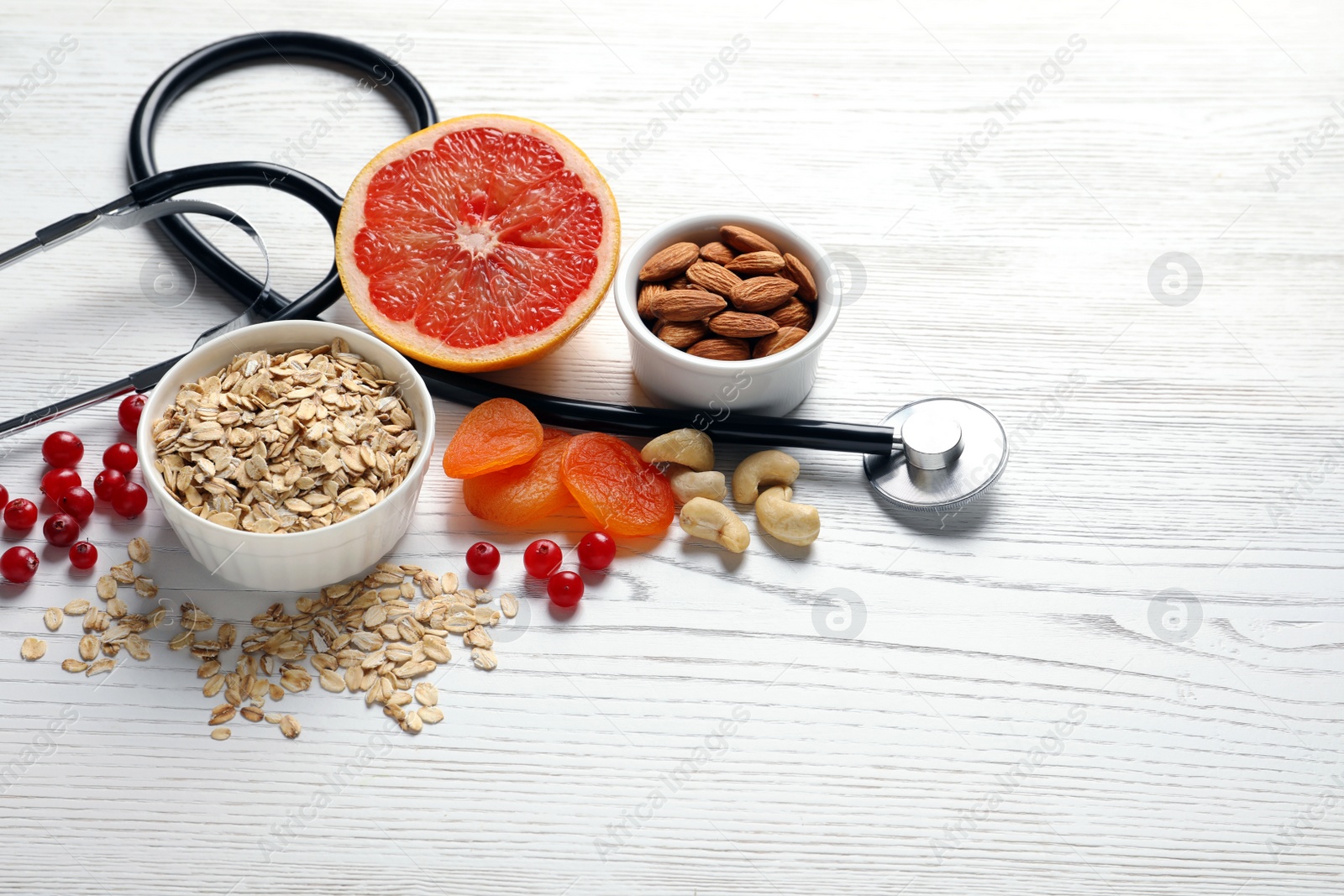 Photo of Heart-healthy products and stethoscope on wooden background, space for text