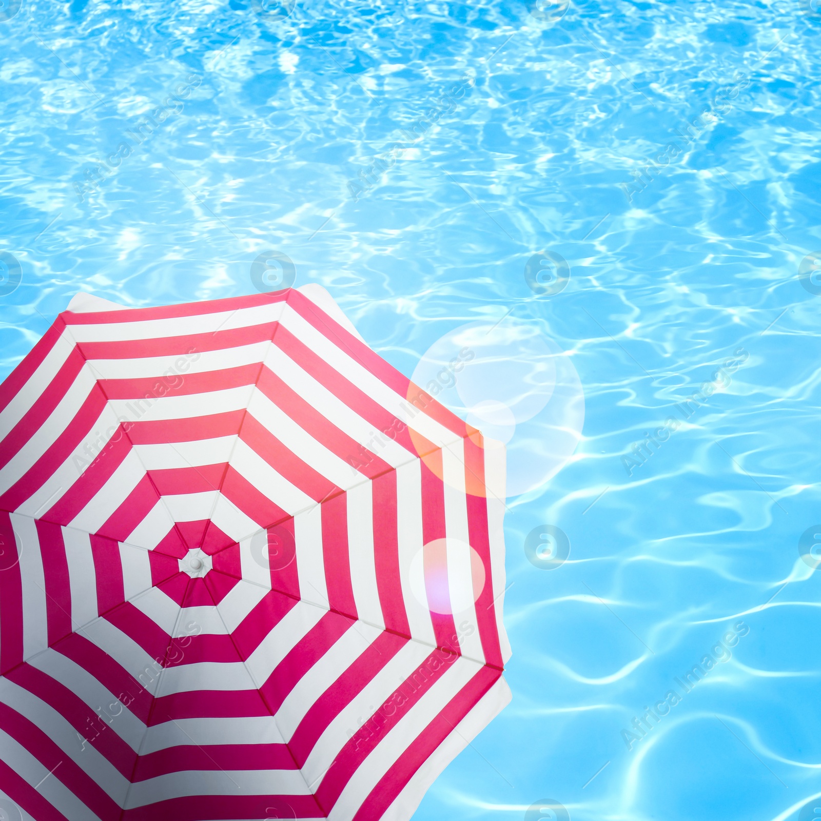 Image of Open beach umbrella and swimming pool. Summer vacation