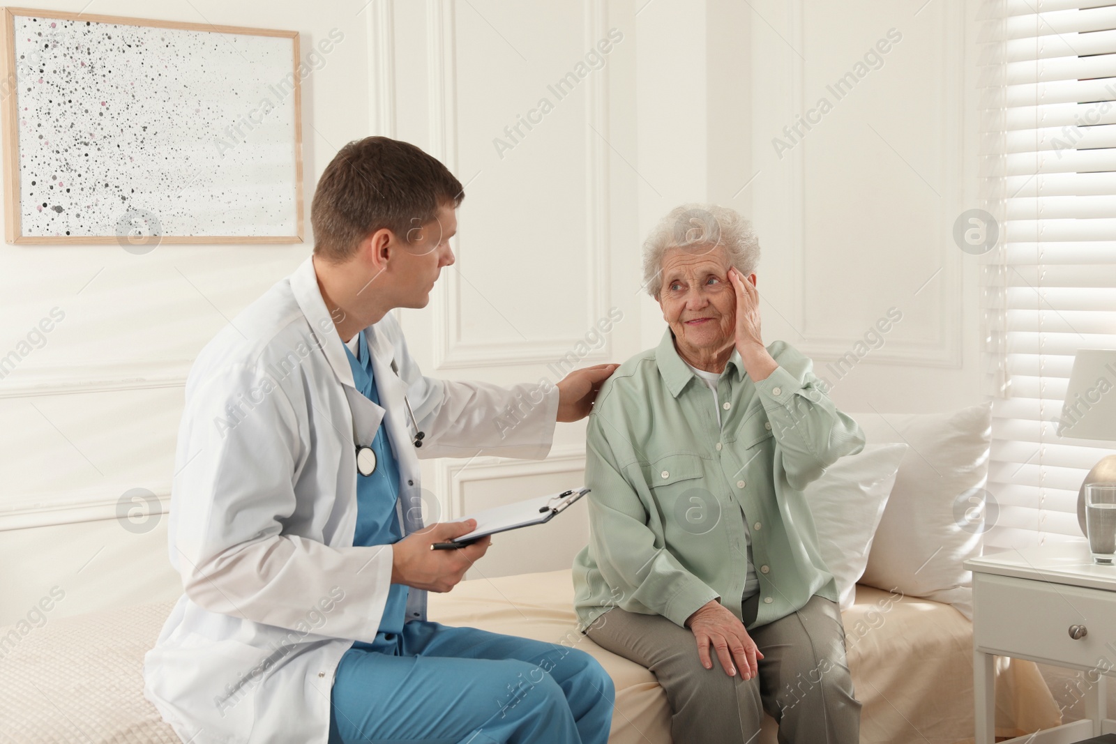 Photo of Caregiver examining senior woman in room. Home health care service