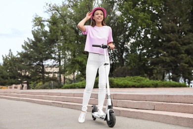 Photo of Young woman with electric kick scooter on city street