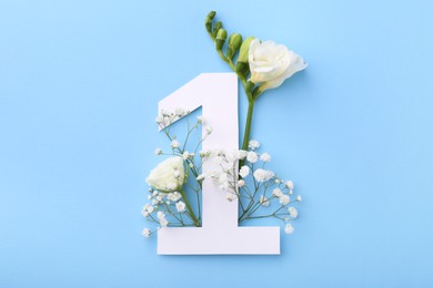 Photo of Paper number 1 and beautiful flowers on light blue background, top view