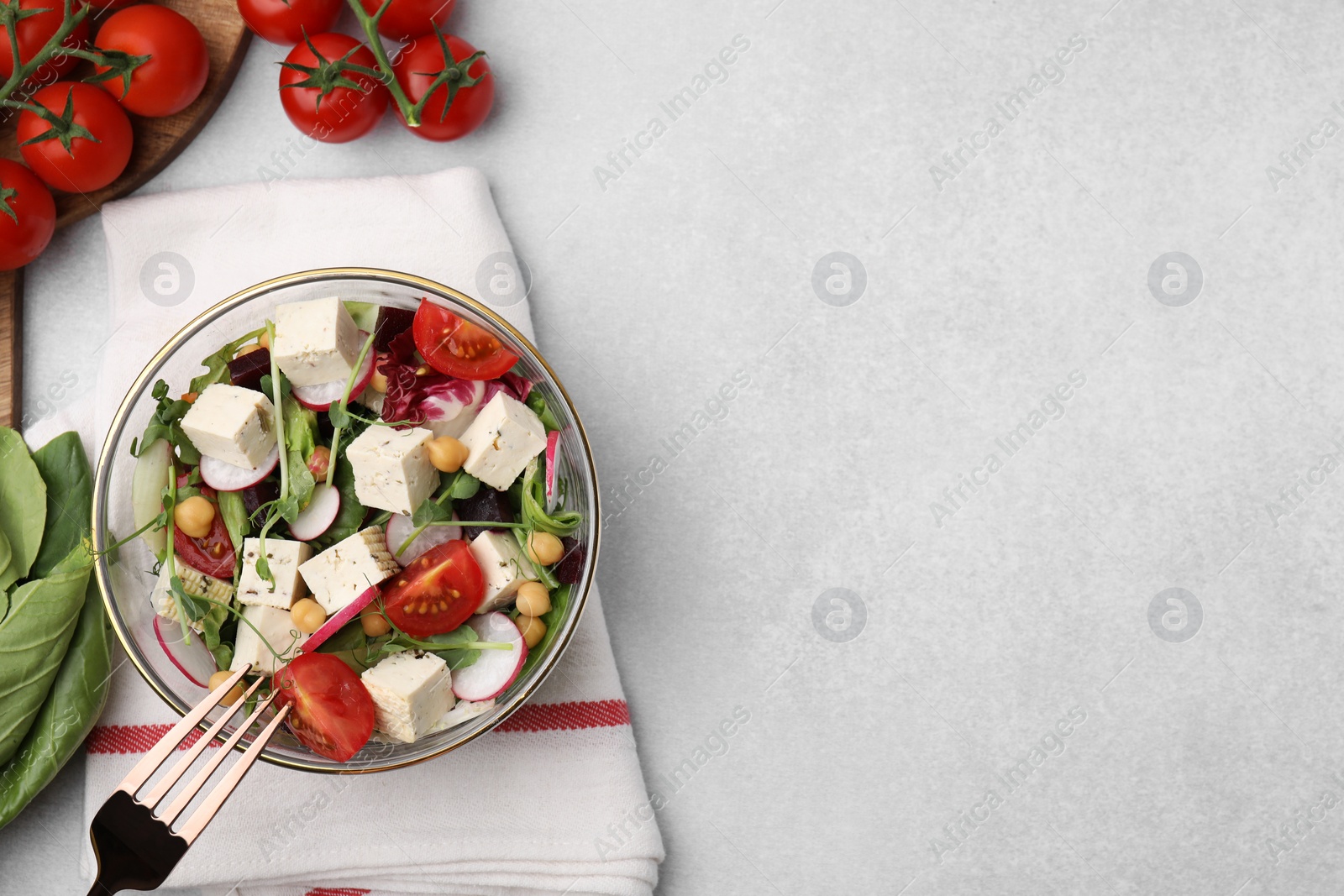 Photo of Tasty salad with tofu and vegetables served on light grey table, flat lay. Space for text