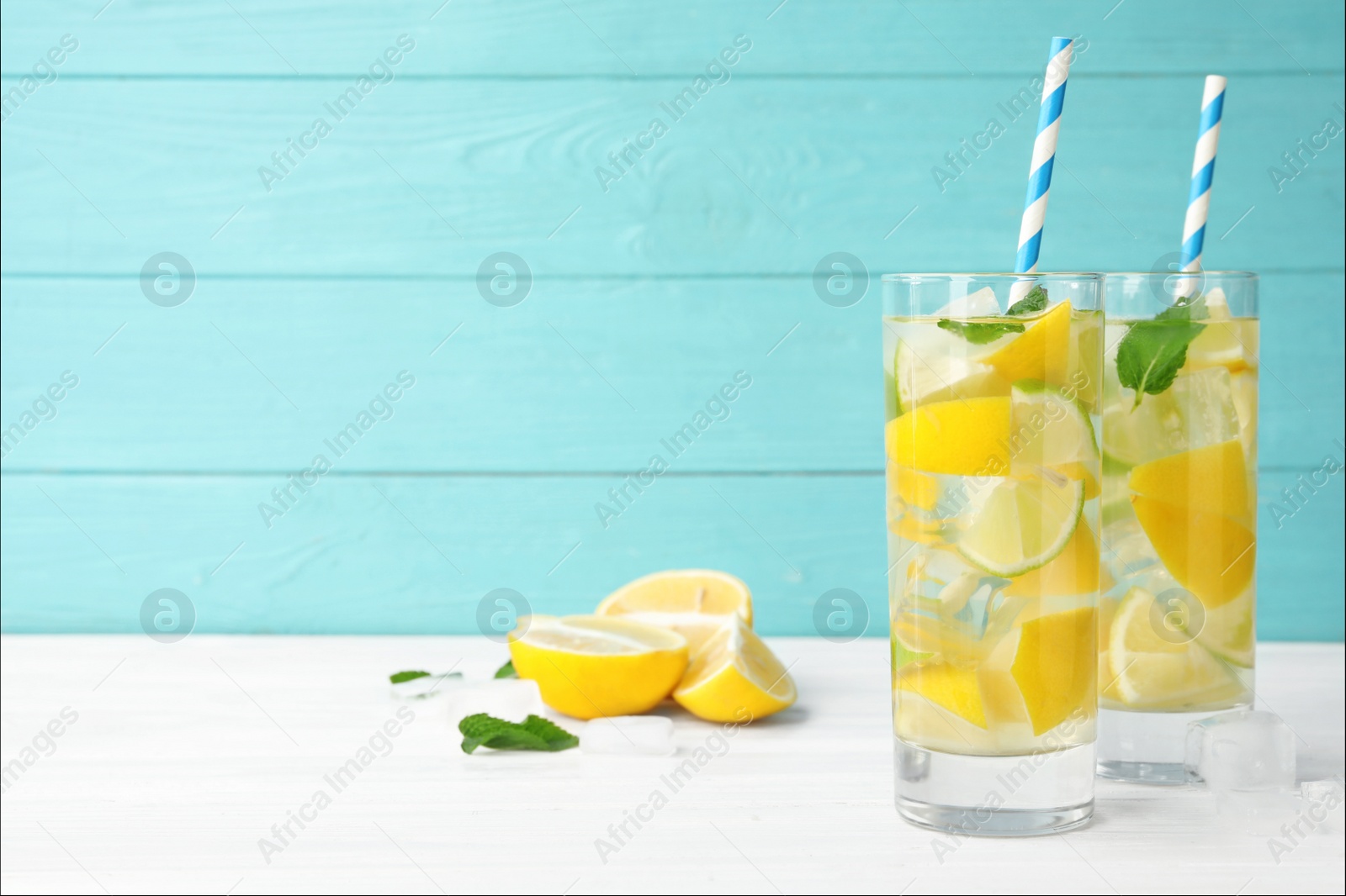Photo of Glasses of refreshing lemonade on table against light blue wooden background, space for text. Summer drink