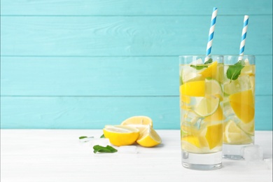 Glasses of refreshing lemonade on table against light blue wooden background, space for text. Summer drink