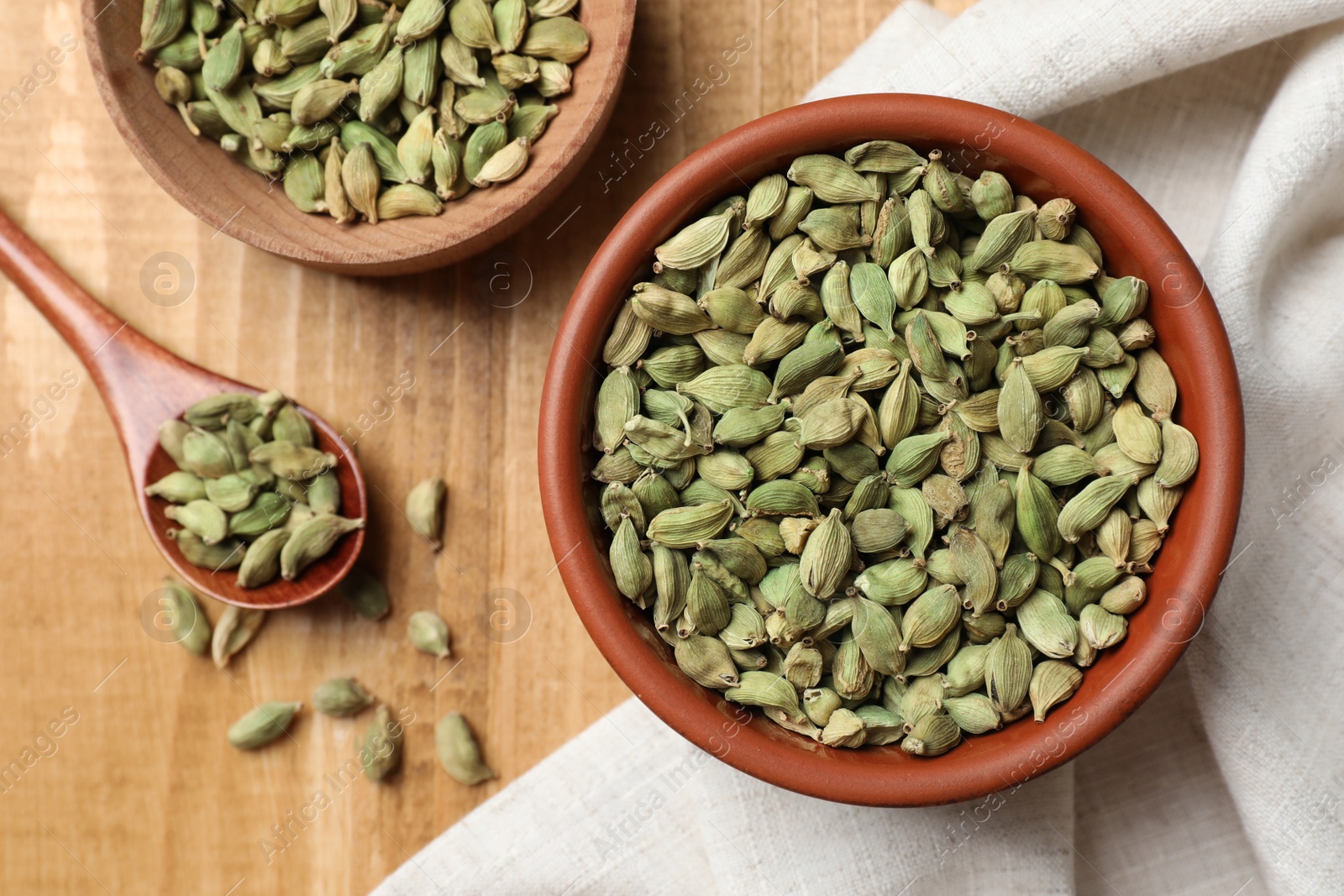 Photo of Dry cardamom pods on wooden table, flat lay