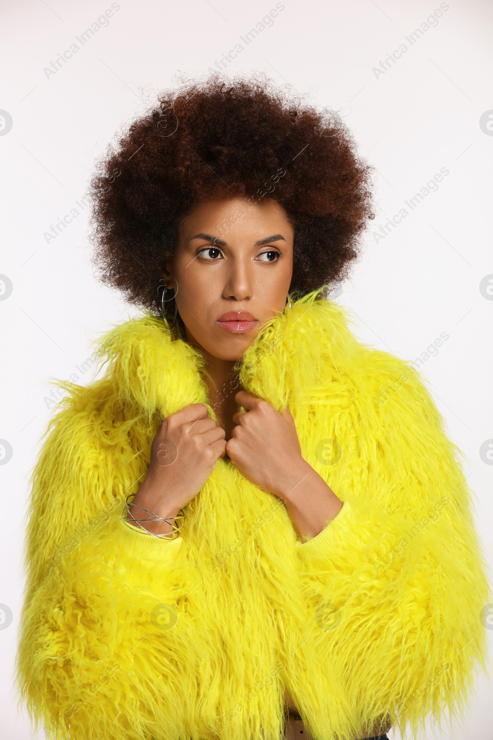 Photo of Portrait of beautiful young woman in stylish yellow fur coat on white background