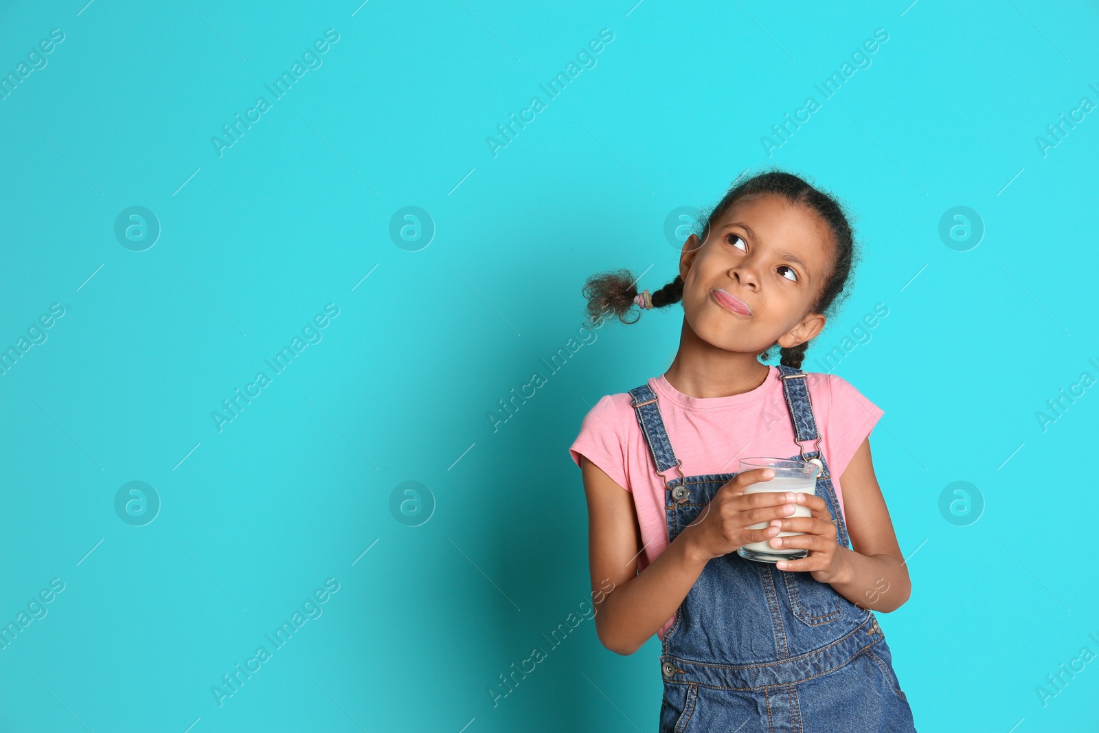 Photo of Adorable African-American girl with glass of milk on color background
