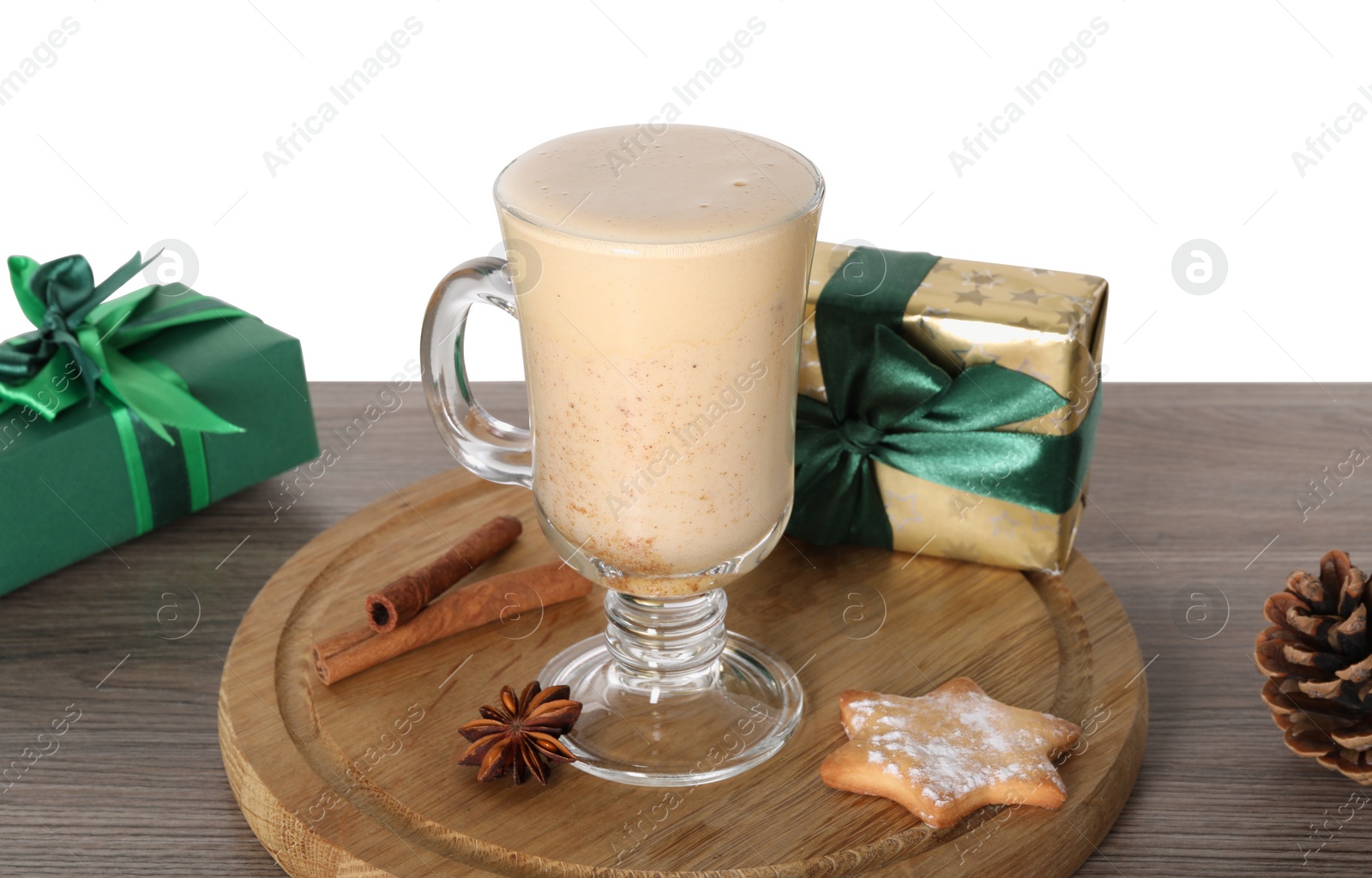 Photo of Delicious eggnog in glass, spices and gift boxes on wooden table against white background