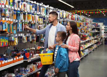 Photo of Family with little boy choosing school stationery in supermarket