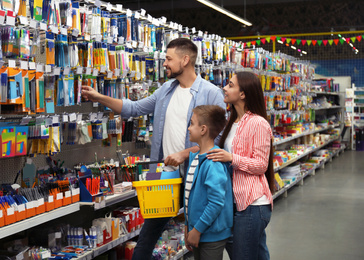 Family with little boy choosing school stationery in supermarket