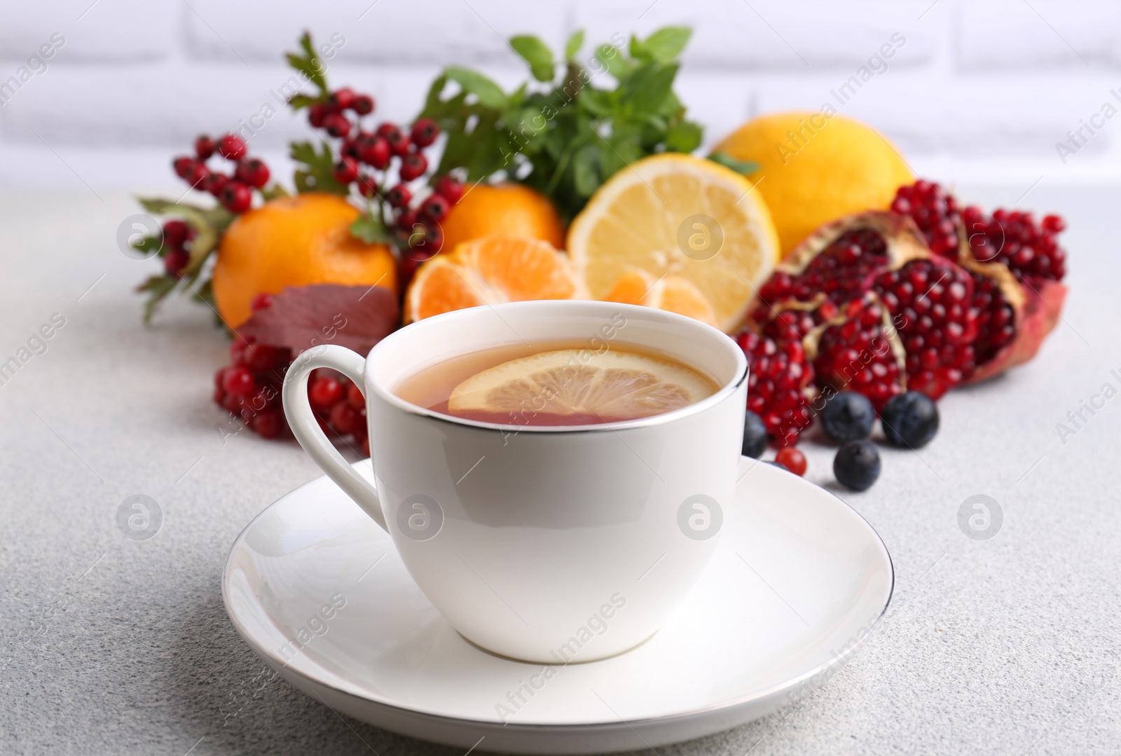 Photo of Cup of delicious immunity boosting tea with ingredients on light grey table