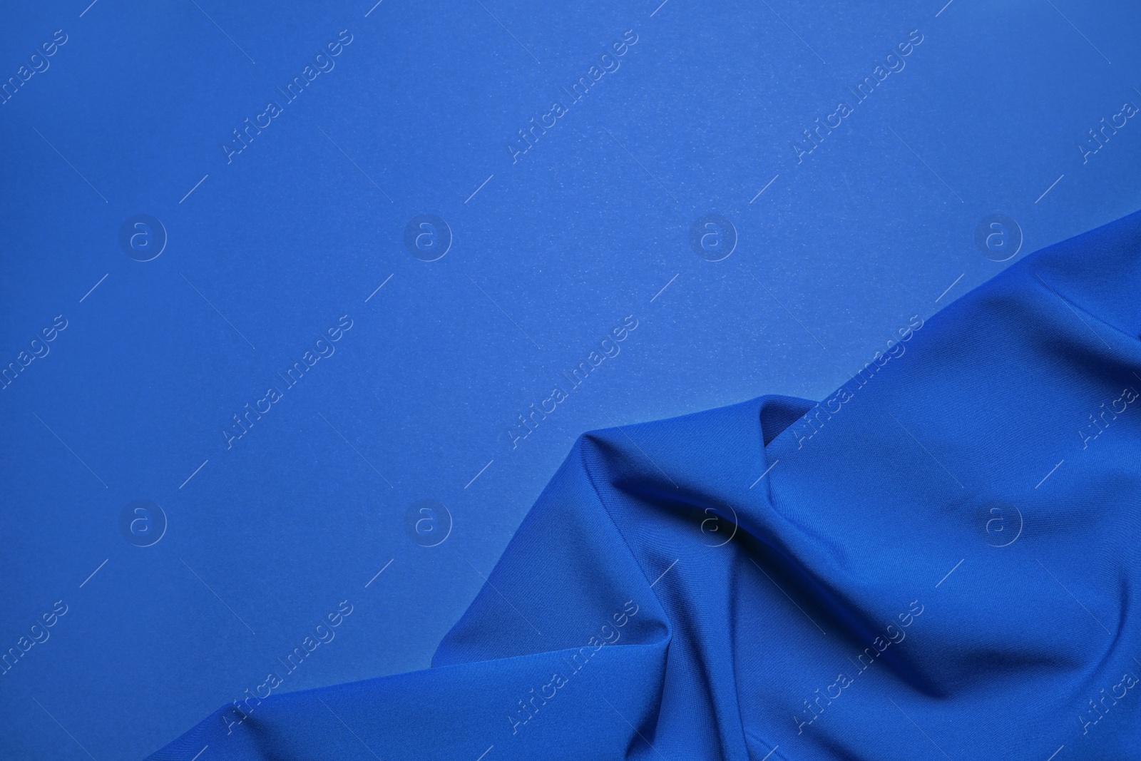 Photo of Crumpled fabric and space for text on bright background, top view. Color of the year 2020 (Classic blue)