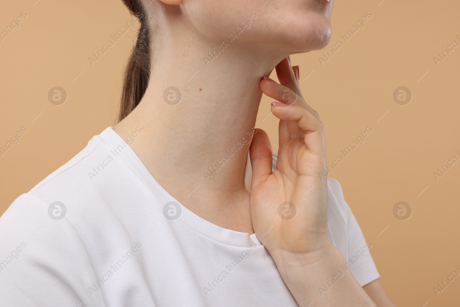 Photo of Woman touching her neck on beige background, closeup