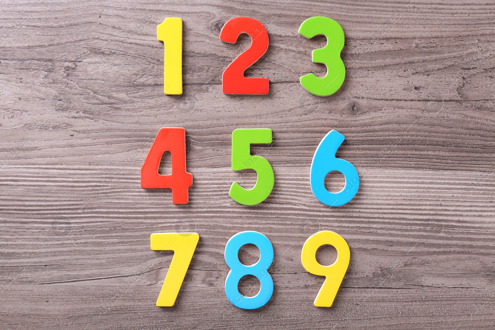 Photo of Colorful numbers on wooden school desk, top view