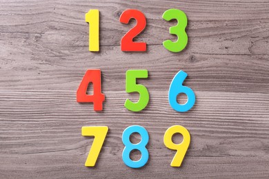 Photo of Colorful numbers on wooden school desk, top view