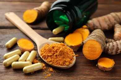 Photo of Aromatic turmeric powder, pills and raw roots on wooden table, closeup