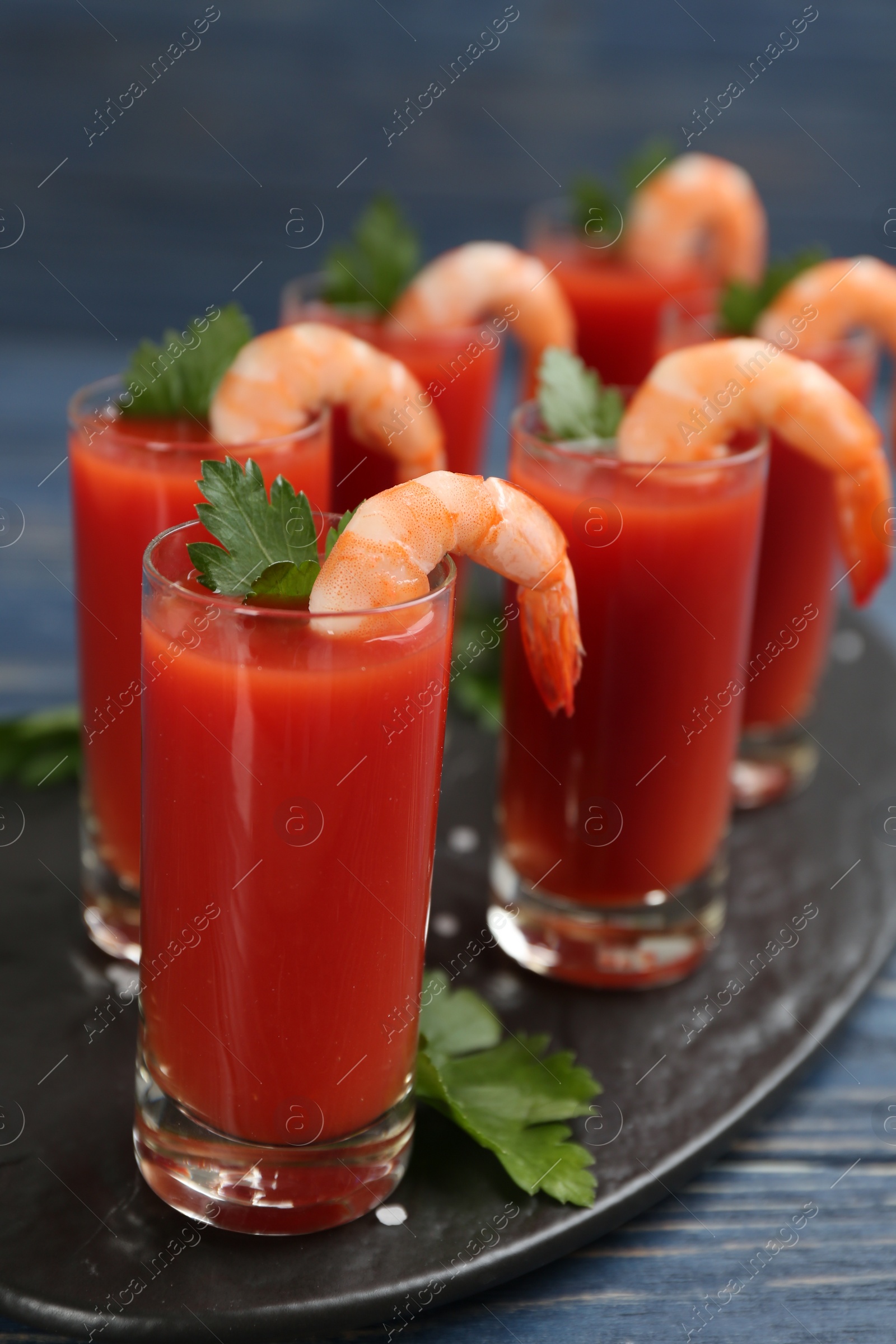 Photo of Glasses of shrimp cocktail with tomato sauce on slate board