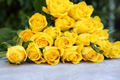 Beautiful bouquet of yellow roses on light table outdoors, closeup