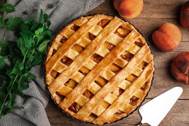 Delicious peach pie and fresh fruits on wooden table, flat lay