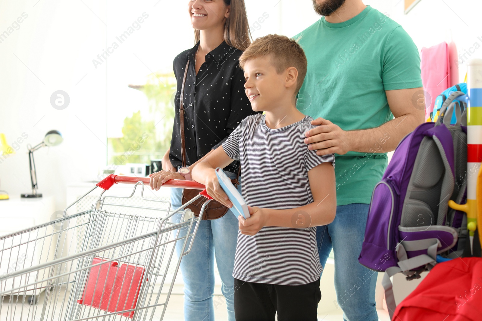 Photo of Little boy choosing school supplies with parents in stationery shop