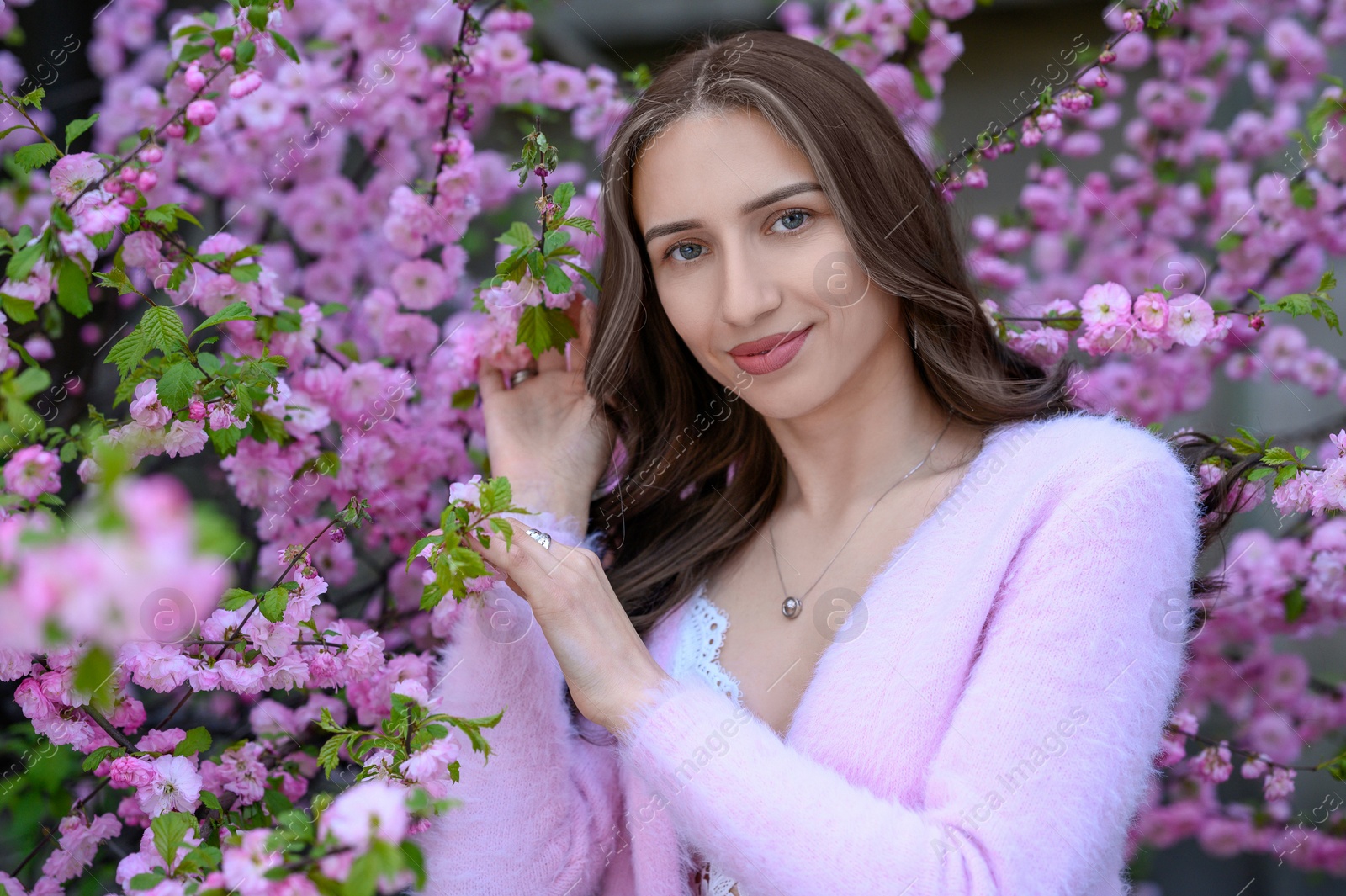 Photo of Beautiful young woman near blossoming sakura tree on spring day