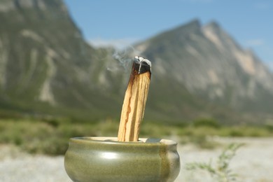 Burning palo santo stick in high mountains, closeup