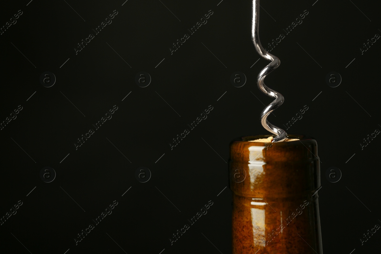 Photo of Bottle of wine and corkscrew on dark background, space for text