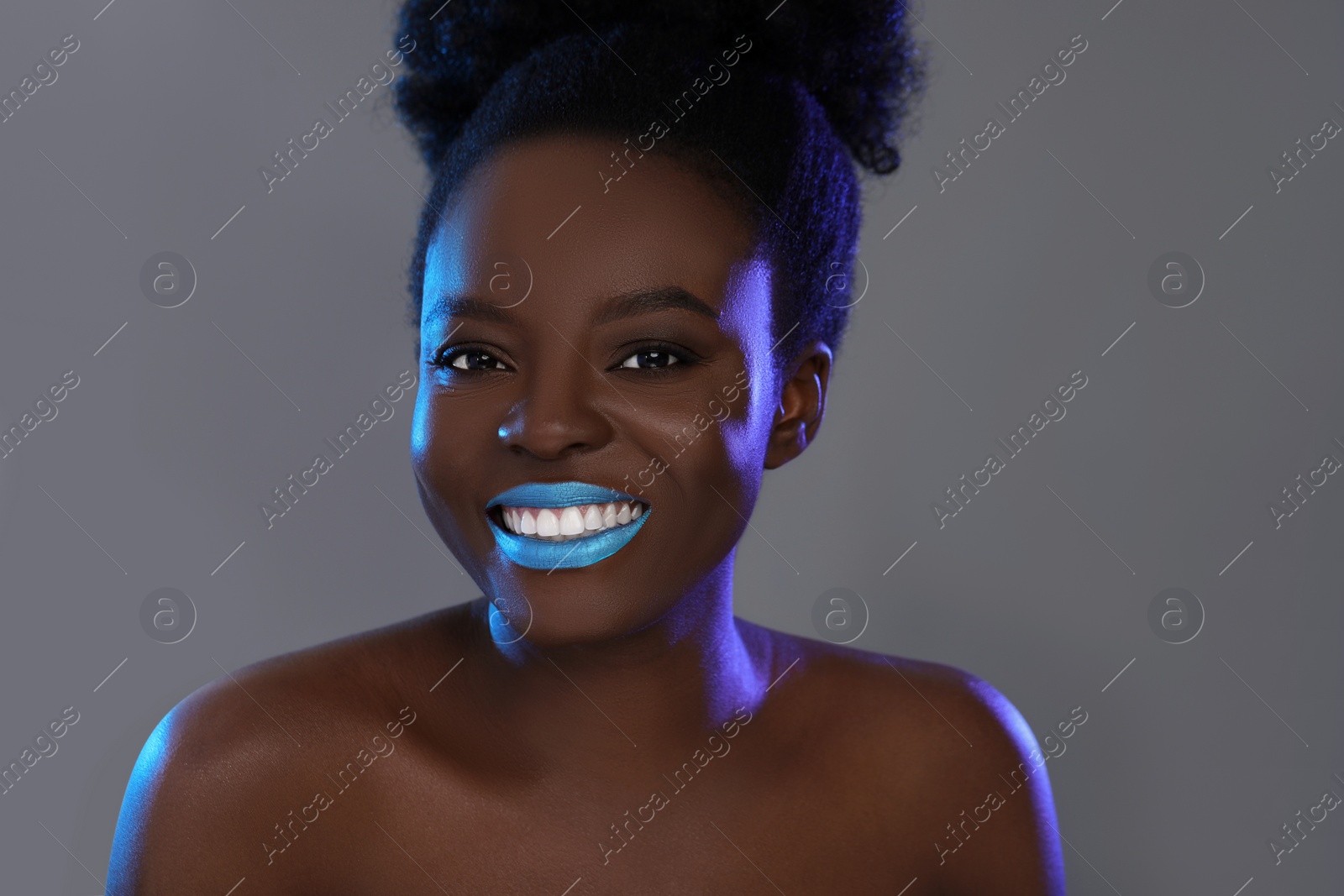 Photo of Fashionable portrait of beautiful happy woman with bright makeup on grey background