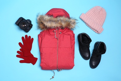 Set of warm clothes and camera on color background, flat lay. Winter vacation