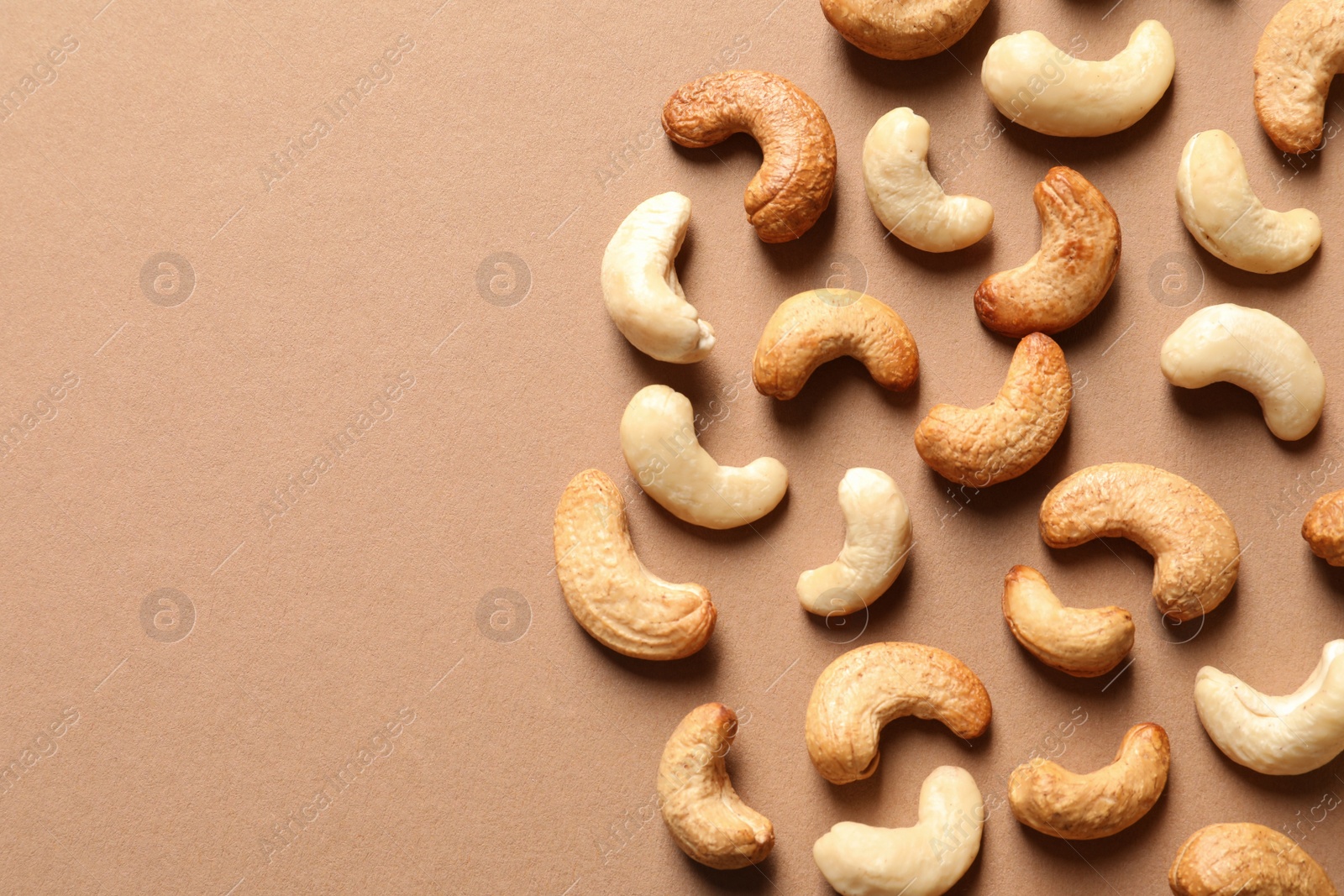 Photo of Tasty cashew nuts on color background, flat lay. Space for text