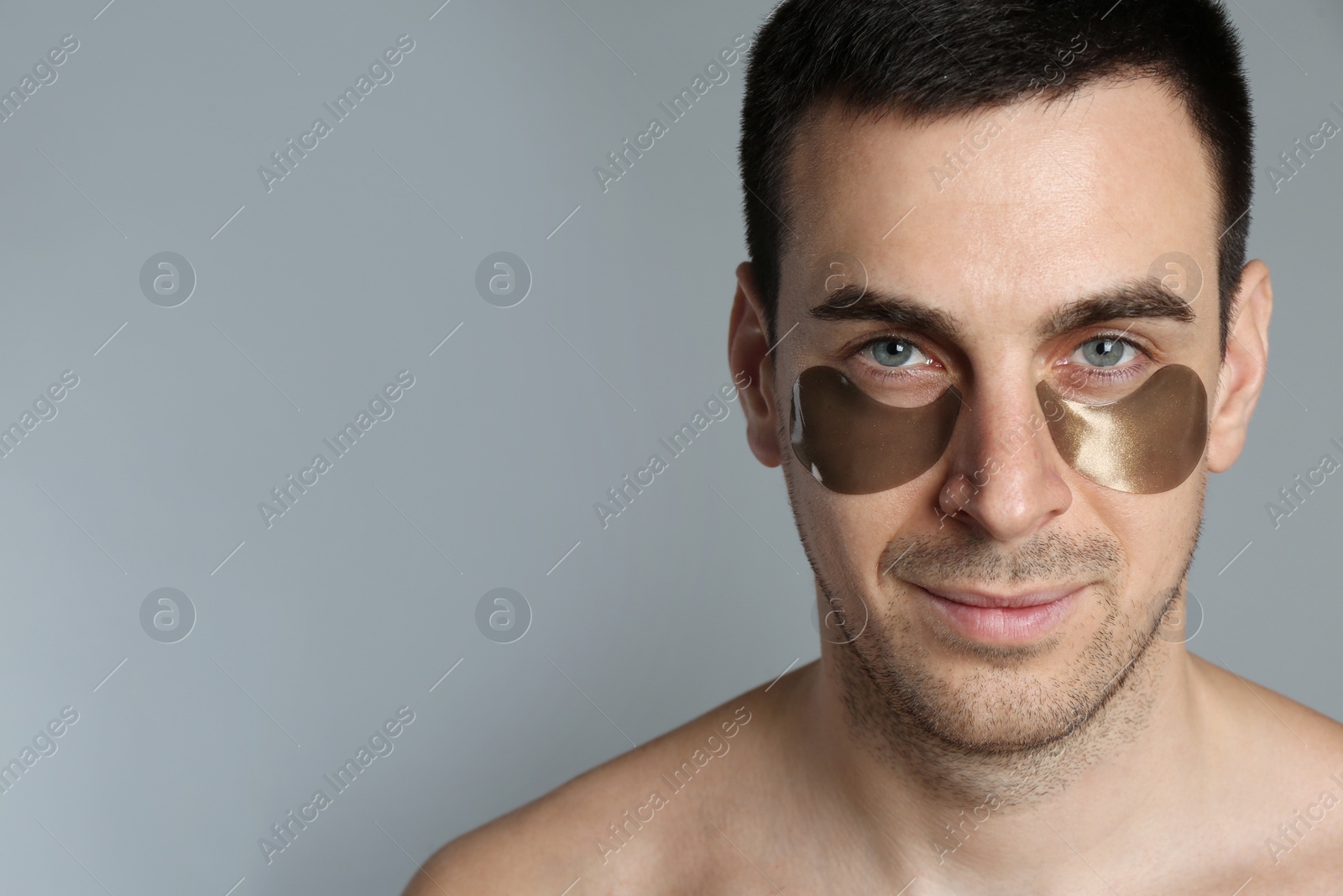 Photo of Young man with under eye patches on grey background. Space for text