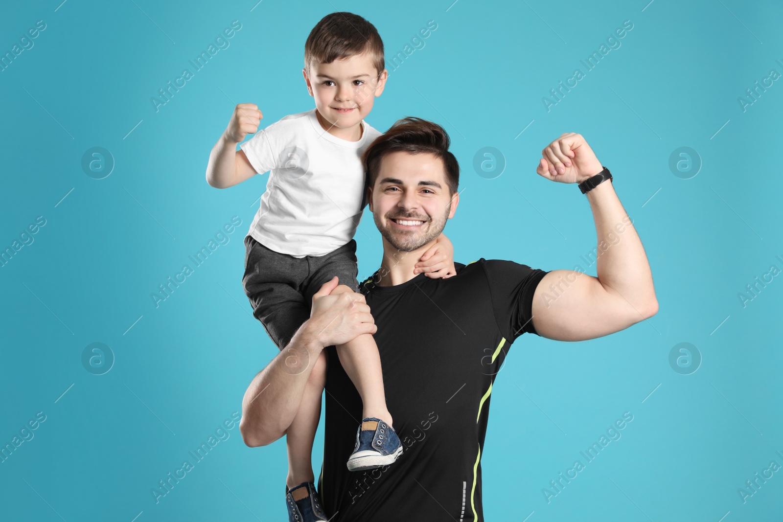 Photo of Portrait of sporty dad and his son on color background