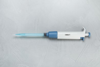 Laboratory analysis. Micropipette with liquid on grey table, top view