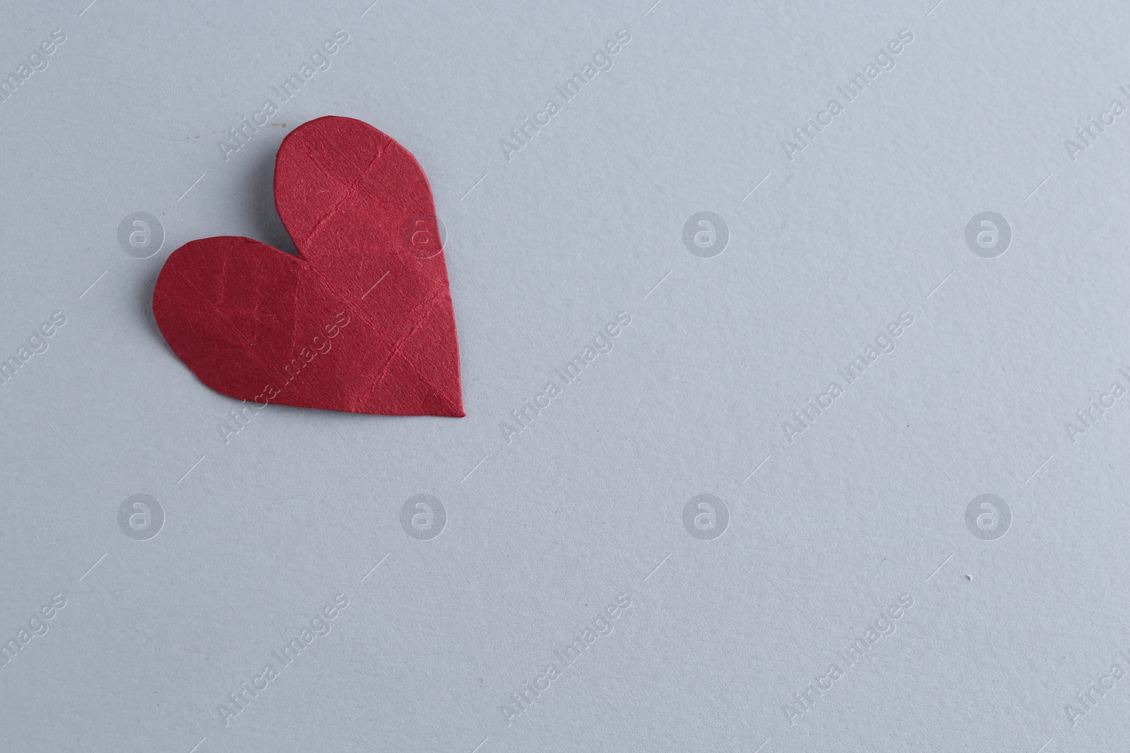 Photo of Red crumpled paper heart on gray background, space for text