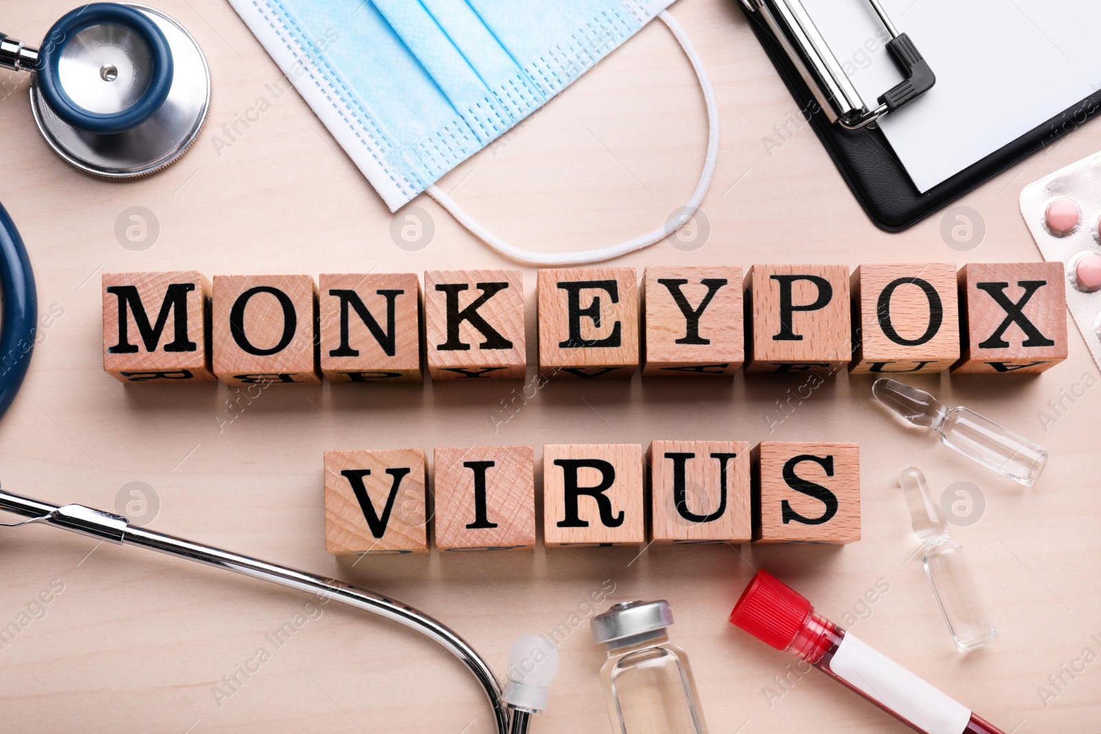 Photo of Flat lay composition with words Monkeypox Virus made of cubes and medical supplies on wooden table