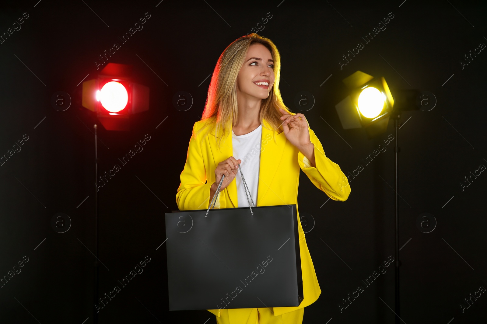 Photo of Happy young woman with shopping bag on dark background. Black Friday Sale