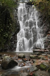 Photo of Picturesque view of beautiful mountain waterfall and rocks outdoors