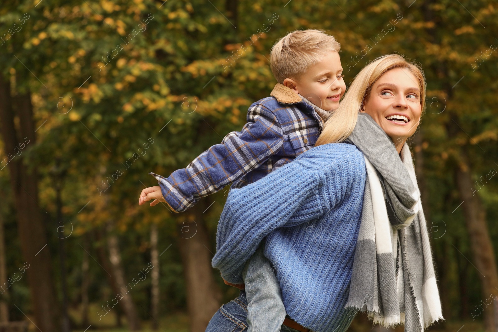 Photo of Happy mother walking with her son in autumn park. Space for text