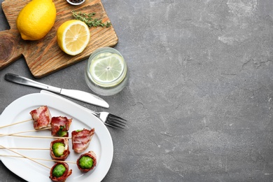 Photo of Brussels sprouts wrapped in bacon served on grey table, flat lay. Space for text