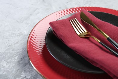 Clean plates, cutlery and napkin on gray table, closeup. Space for text