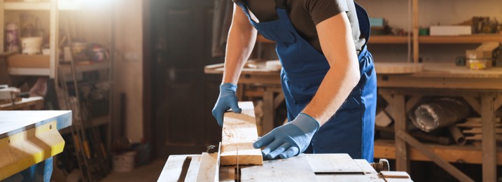 Image of Professional carpenter working with wood in shop, closeup. Banner design