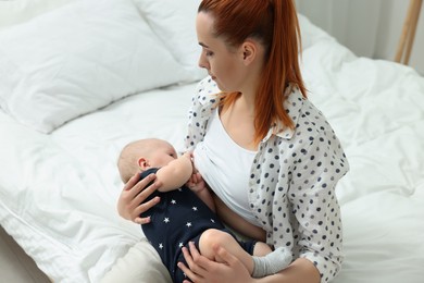 Mother breastfeeding her little baby in bedroom