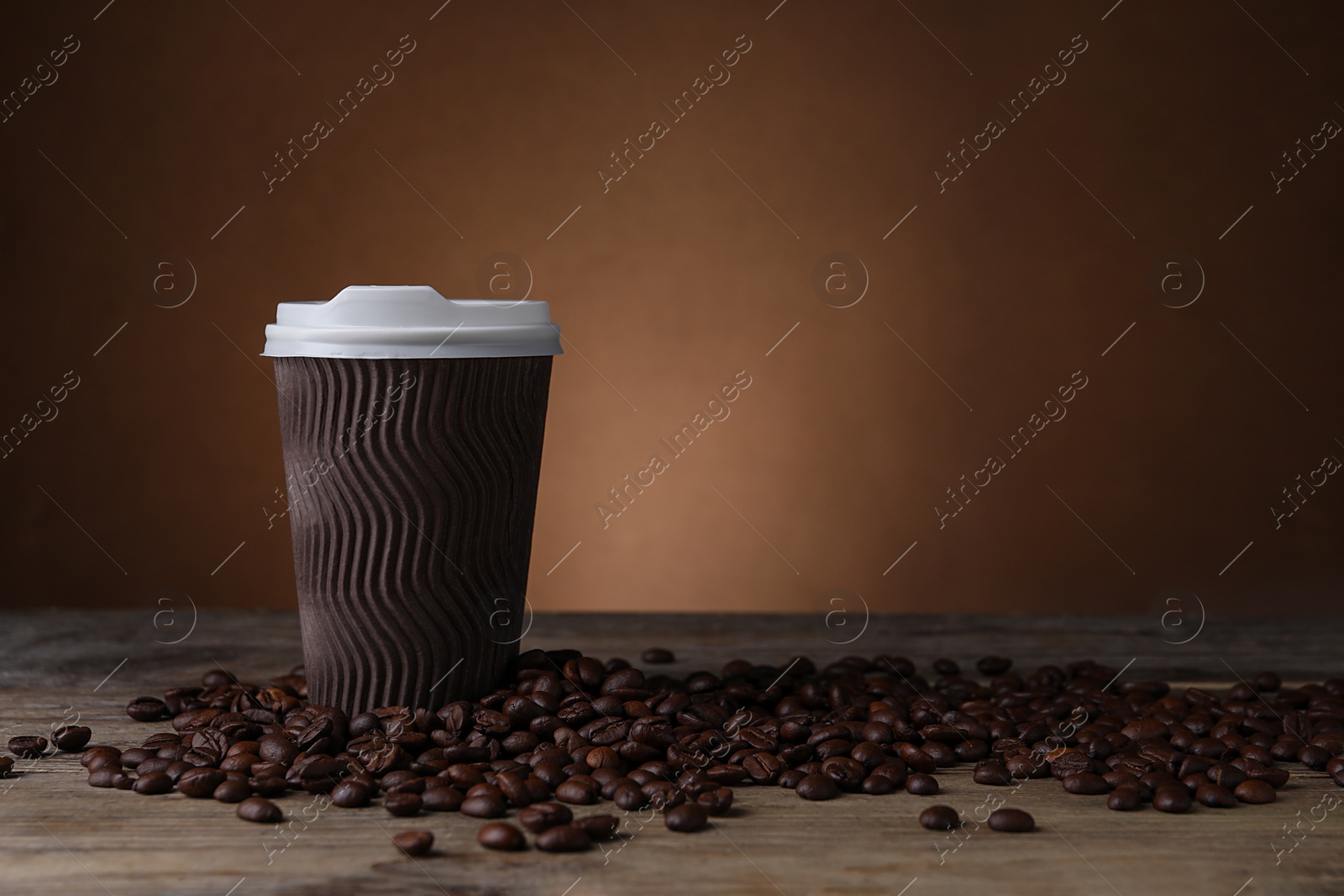 Photo of Coffee to go. Paper cup and roasted beans on wooden table, space for text