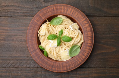 Photo of Delicious pasta with brie cheese and basil leaves on wooden table, top view